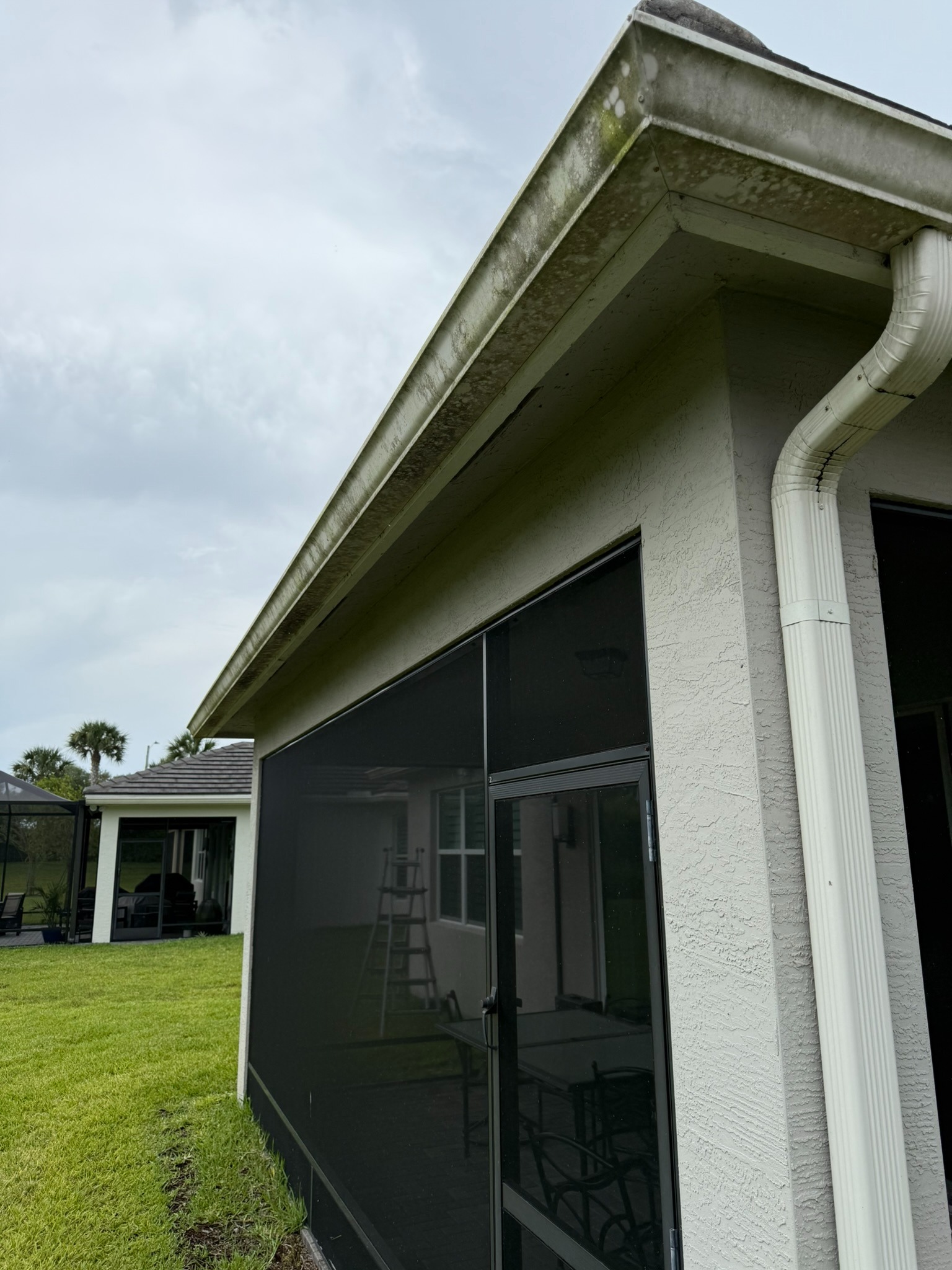 Gutter cleaning, screened lanai corner in Tradition, FL — before